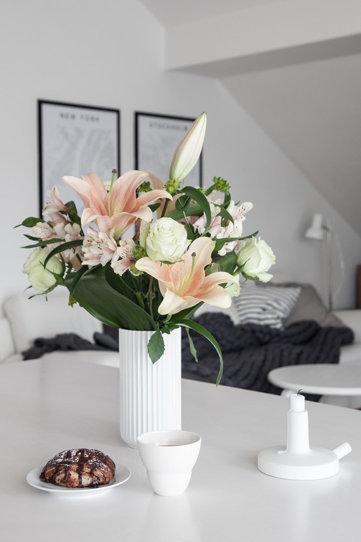 گل های مصنوعی سفید و صورتی در گلدان سرامیکی سفید که با شاخ و برگ طبیعی دیزاین شده است