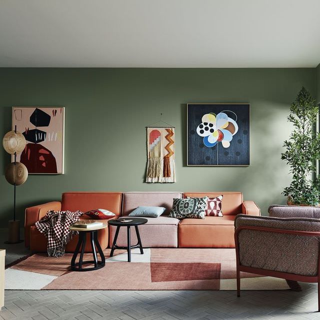 دکوراسیون سبز رنگ دیوارهای نشیمن که مبل و فرش نارنجی در آن استفاده شده است