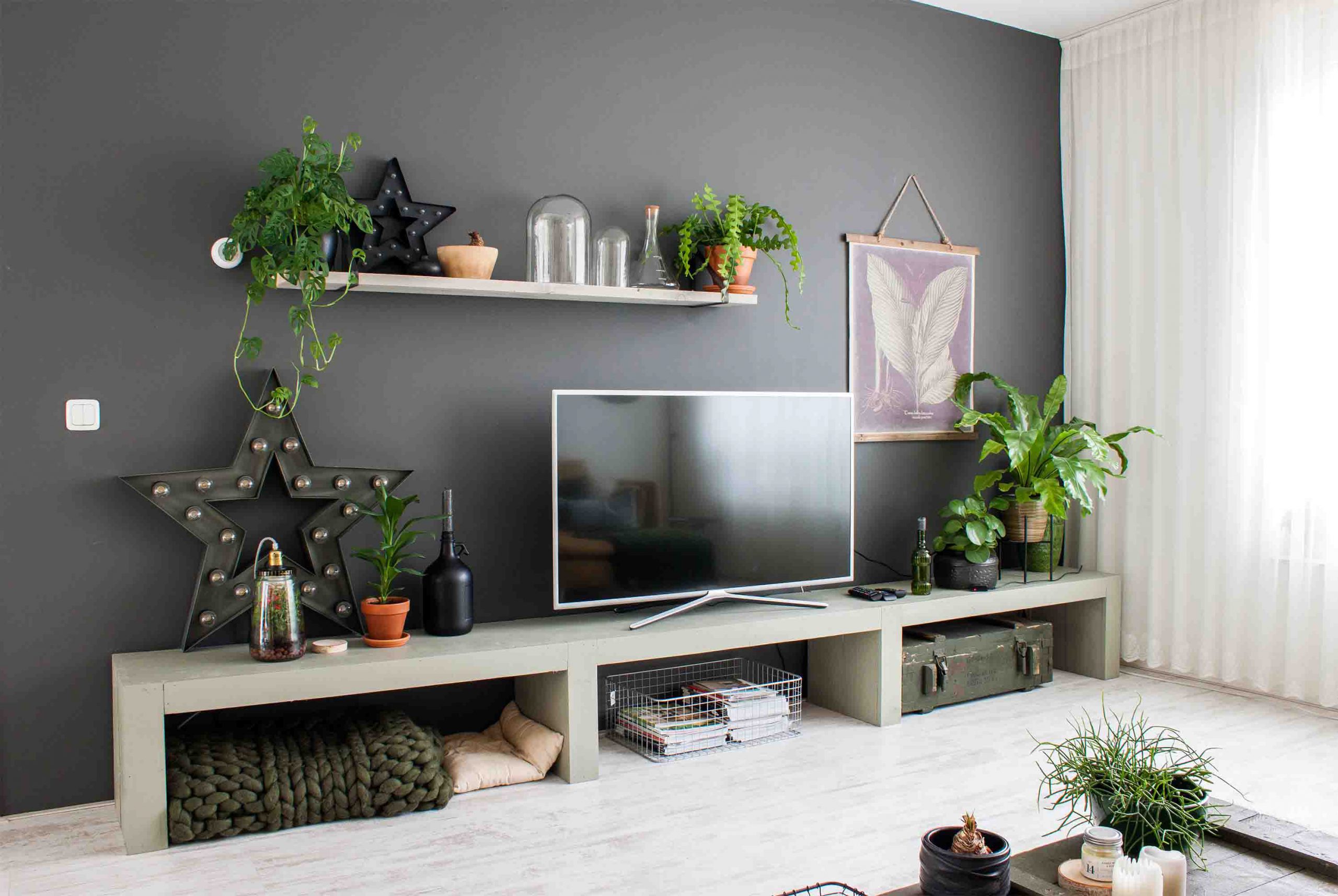 دیزاین دیوار پشت تلویزیون با شلف چوبی، قاب عکس و گلدان
