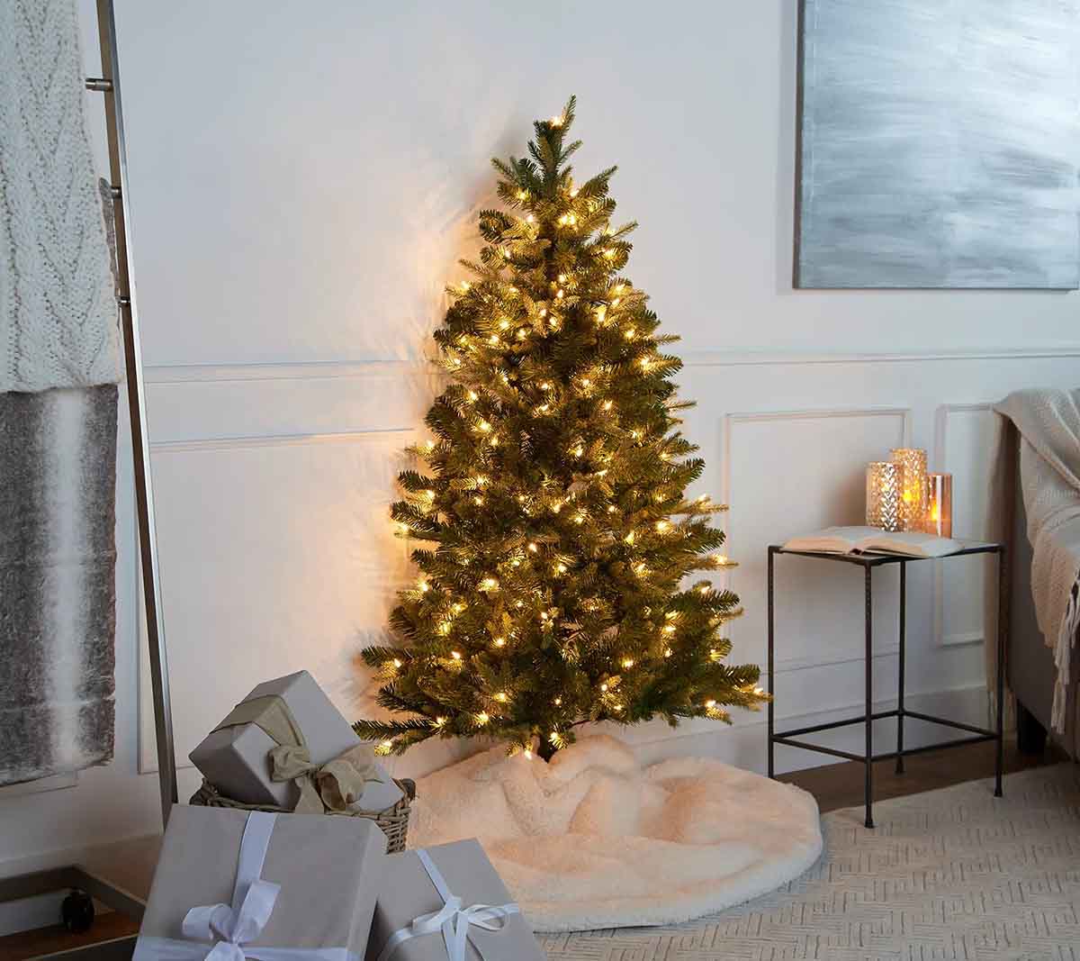 تزیین درخت کریسمس با ریسه نوری، دامن سفید و کادوهای خاکستری