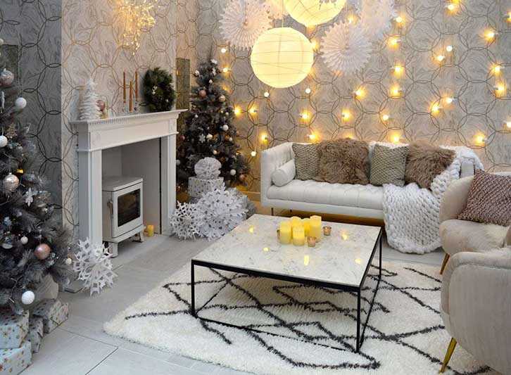 تزیین کریسمس در نشیمن خانه با درخت و ریسه نوری و شمع برقی با تم سفید اسکاندیناوی