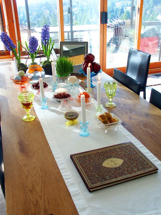 چیدمان سفره هفت سین روی میز ناهار خوری با ظروف تزئینی کریستال و گل سنبل
