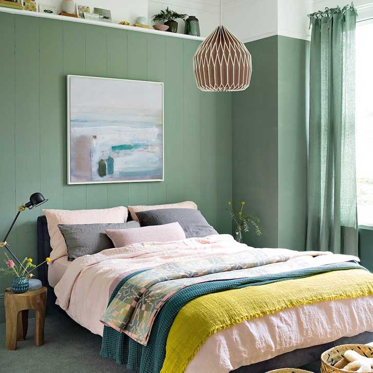 رنگ اتاق خواب سبز و صورتی با دیوارهای سبز تیره و روتختی صورتی و شال تخت سبز