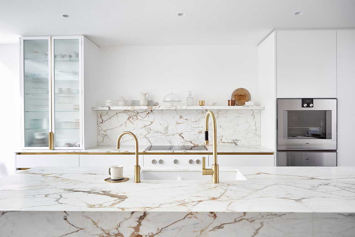کابینت سفید طلایی مات در آشپزخانه مدرن با شیر آلات طلایی و سنگ مرمر طلایی