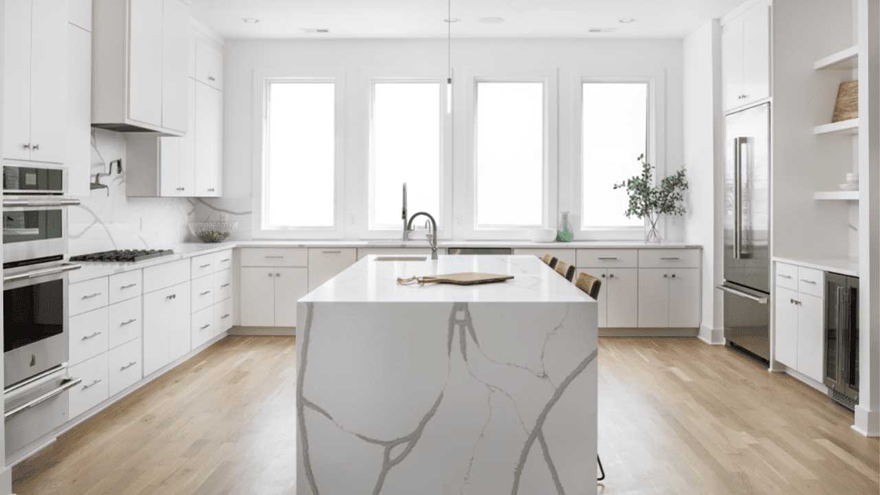 کابینت سفید یک دست مات در آشپزخانه مدرن جزیره دار بزرگ با بین کابینتی و روکابینتی مرمر سفید