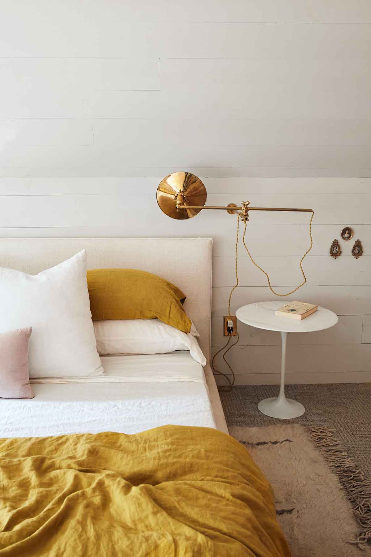 دکوراسیون سفید طلایی اتاق خواب مدرن با اکسسوری طلایی و روتختی زرد خردلی