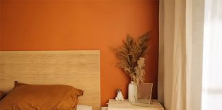 پانختی چوبی تخت چوبی در اتاق خواب با دیوار تاکیدی نارنجی