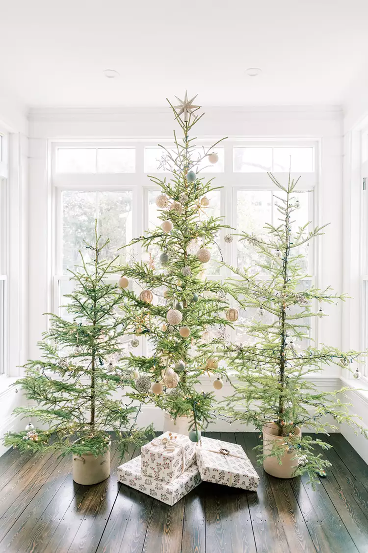 تزیین کریمس در خانه با سه درخت کریسمس مینیمال و توپ های نقره ای و طلایی