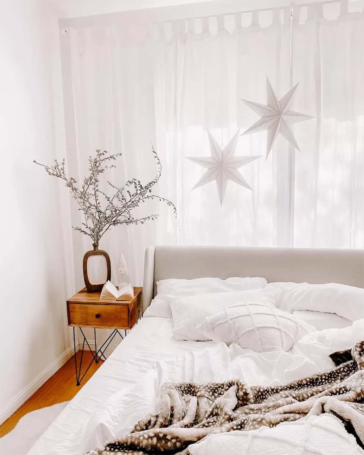 تزیین کریسمس اتاق خواب با ستاره های آویز کریسمس و گلدانی از شاخه های خشک شده