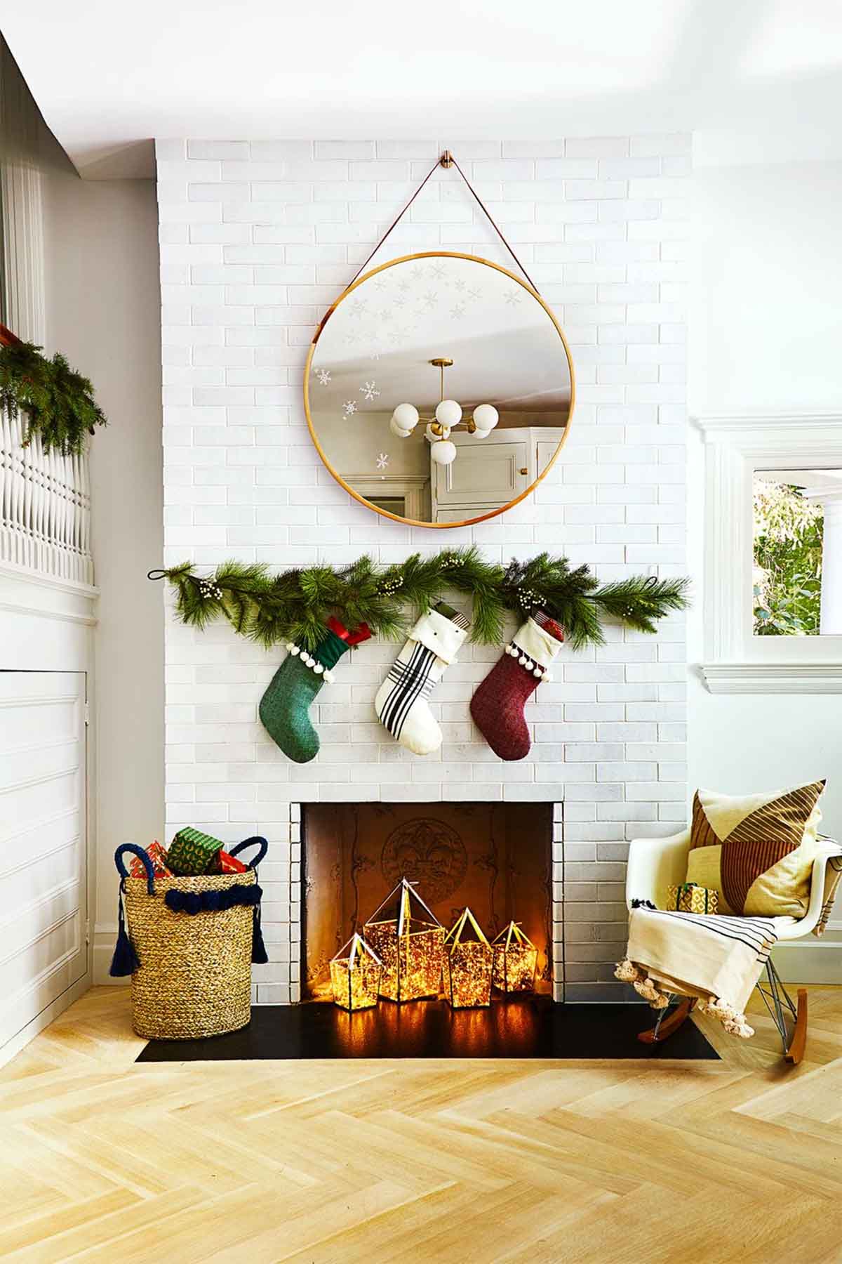 تزیین کریسمس در خانه با دیزاین جوراب بالای شومینه و شاخ و برگ های سبز